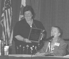 At the 2000 NFB Convention, Sharon Maneki (right) presents a placque to Denise Mackenstadt (left), as the 2000 recipient of the Distinguished Educator of Blind Children Award.