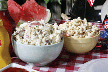 Bowls of macaroni and potato salad on a picnic table.