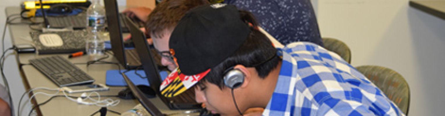 Four blind students work on laptop computers while wearing headphones.