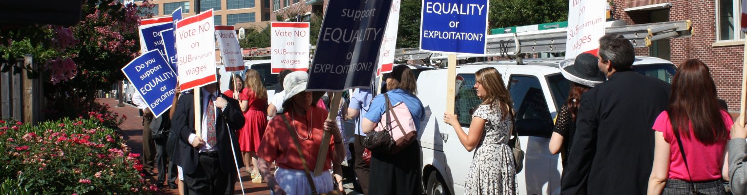 A protest with blind protesters holding signs that say "Vote No on Subminimum Wages" and "Do You Support Equality or Exploitation?"