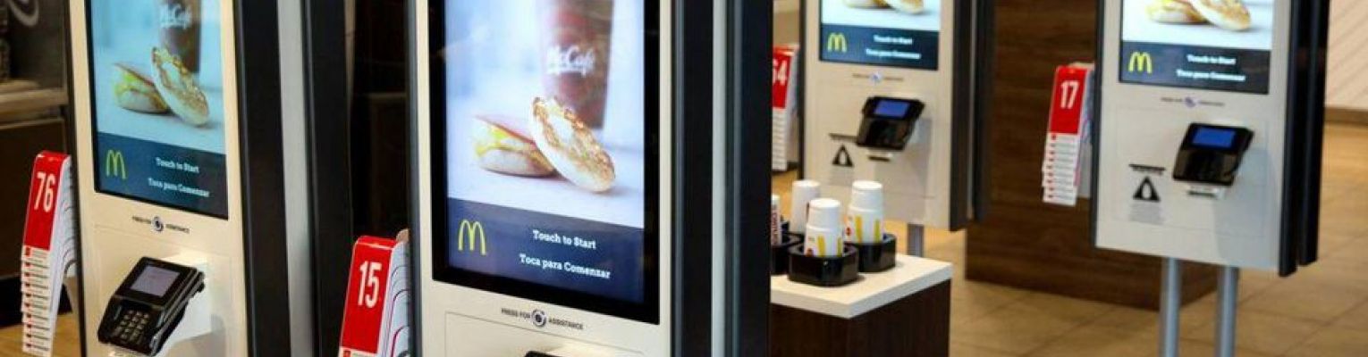 Four touch screen devices with McDonald's logo that say, "Order Here"