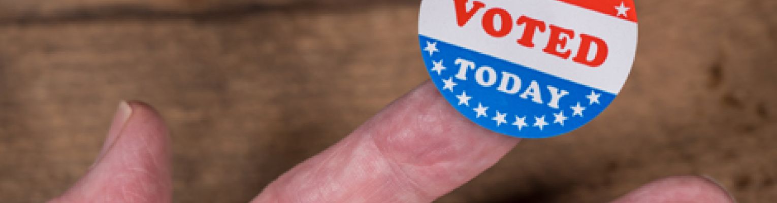 An "I voted" sticker rests on a person's finger.