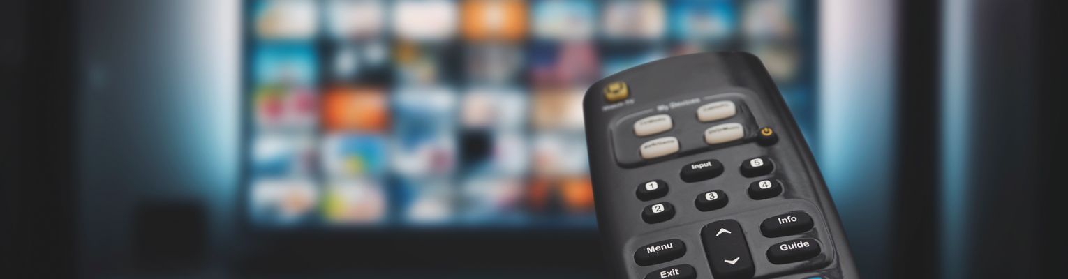Television remote points toward a blurred tv screen.