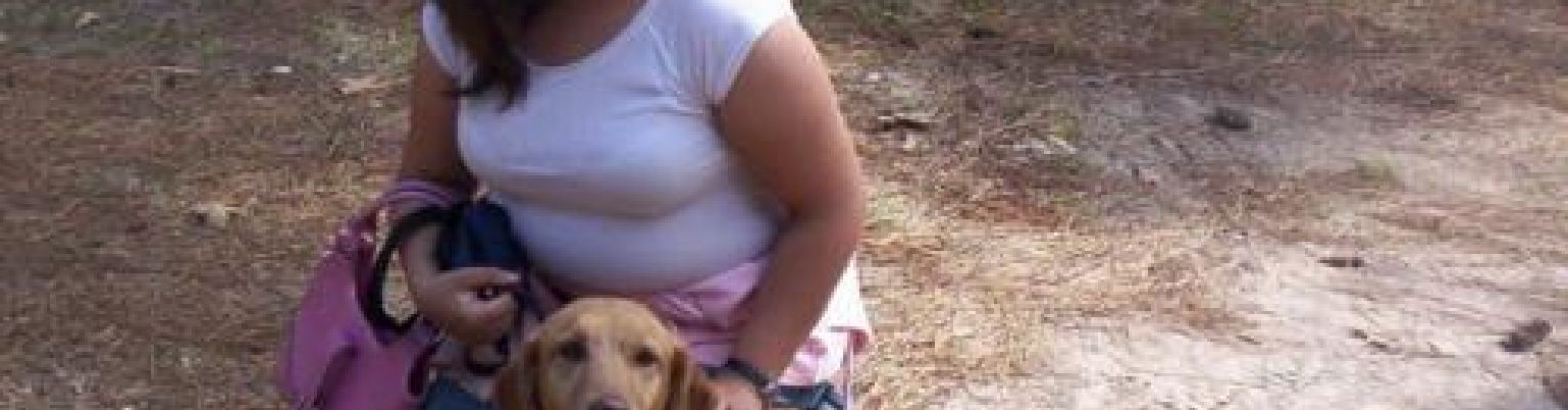 Danielle sits on the ground with her dog, Abbie.