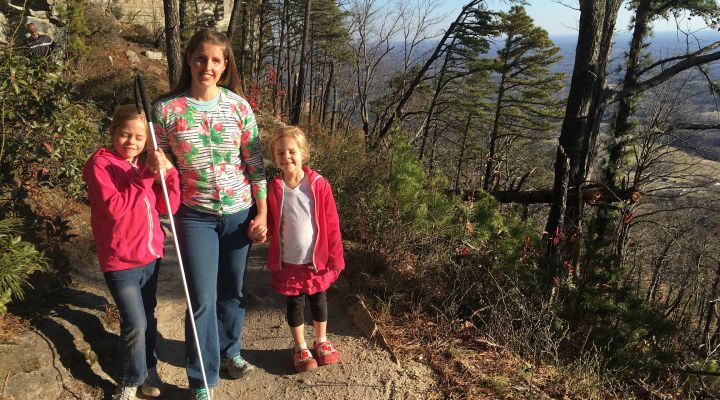 A blind family poses for a picture on a hiking trail.
