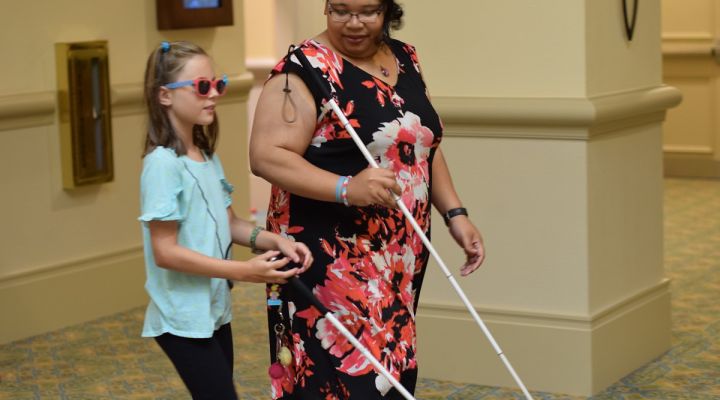 A blind woman and a blind girl walk with white canes.