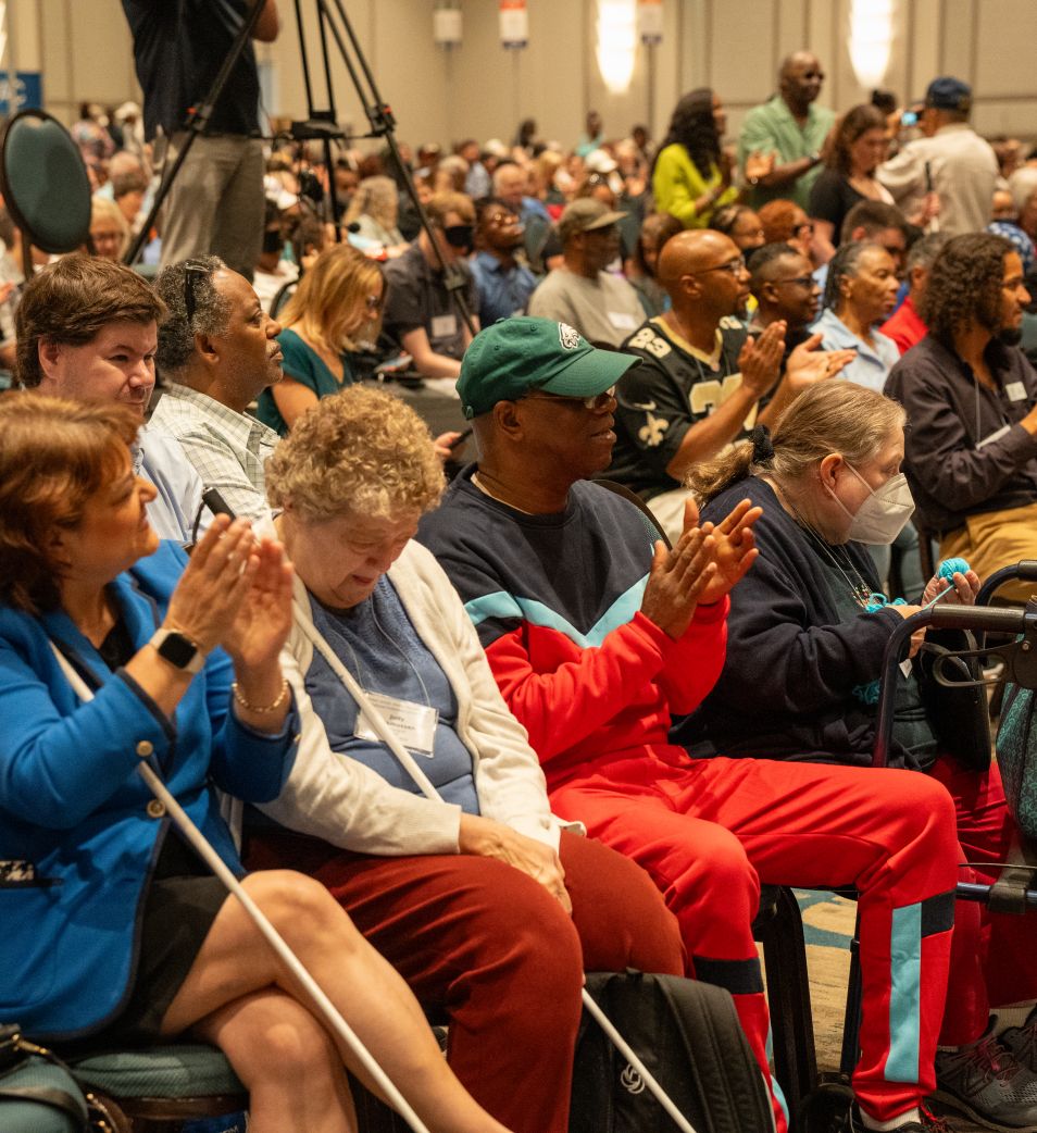 Blind people smile and clap during the general opening session.