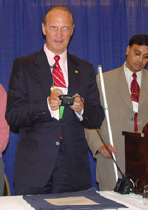 In front of a ballroom full of breathless watchers, Jim Gashel uses a Kurzweil National Federation of the Blind Reader to photograph, scan, and read aloud a page of text.