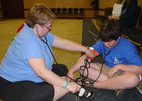 Heather Frit instructs Michael Taboada from Louisiana in the fine points of taking blood pressure.