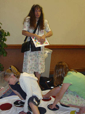 Alison Van Etten, Katie Kress, and Melissa Riccobono play a Brille version of Twister at the Braille carnival.