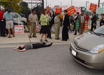 In a bit of street theater the driver of a Toyota Prius, rented for the occasion, pretended to strike and kill Rosy Carranza of the NFB�s Affiliate Action staff. Here she lies in the street following the accident.