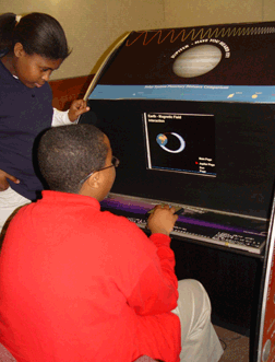 A number of young people were present at the event. Here, two of them listen to an audible report of magnetic field interaction on the solar system planetary distance comparison machine on loan that day from the Goddard Space Flight Center.