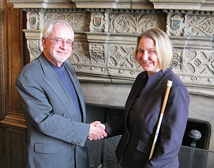 Dick Davis and Shawn Mayo shake hands in front of the elaborate Victorian fireplace in the Pillsbury Mansion.