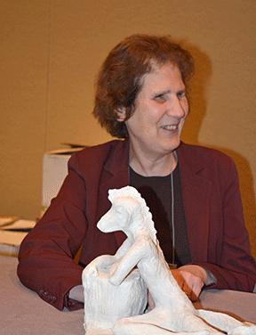 Debbie sits with her sculpture Transformation in front of her.