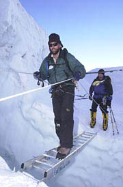 Erik Weihenmayer walks on a ladder across a crevasse.