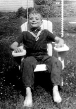 Photo of Marc Maurer as a child sitting in a swing with his bare feet resting in the grass.