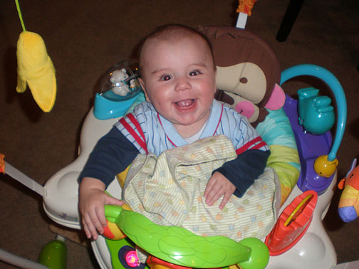 Gavin bounces in a jumper swing with toys