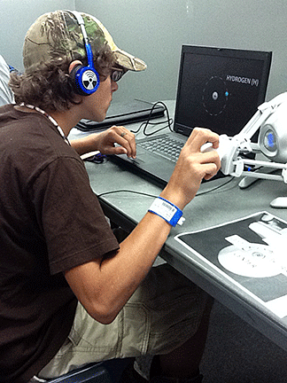 Using the Novint Falcon, a student examines the hydrogen atom pictured on his computer.