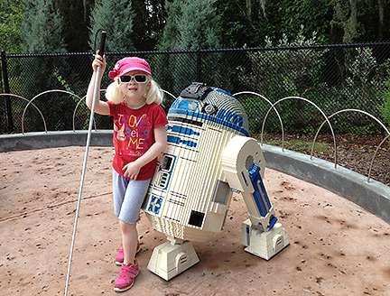 Chloe Darlington in a sandbox, leaning on R2D2 from Star Wars