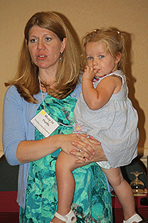 Mary Jo Hartle speaks before a group as she holds her young daughter, Kayla.