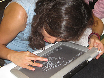 A girl at NFB Camp works on a tactile drawing.