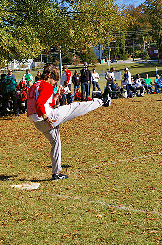 The boy follows through after kicking the ball.