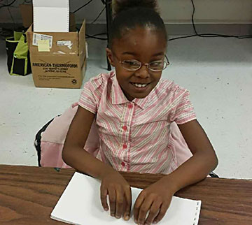 Allonah reads a Braille page.