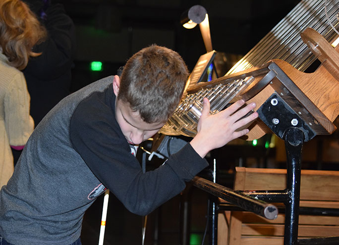 Dimitri Shaposhnikova listens to wind tubes at the Exploratium during STEM2U San Francisco.