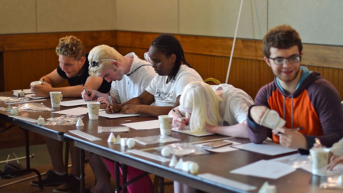 Five STEM EQ students work at a table making tactile drawings. 