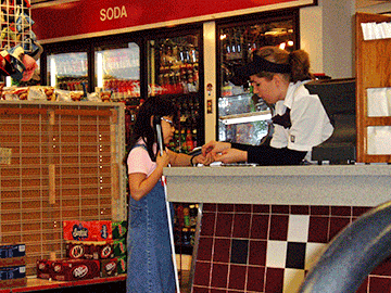 Cane in hand, Ashleah pays at the counter of a convenience store.