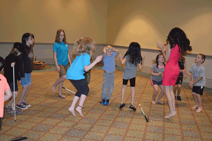 A group of blind and sighted children dance together.