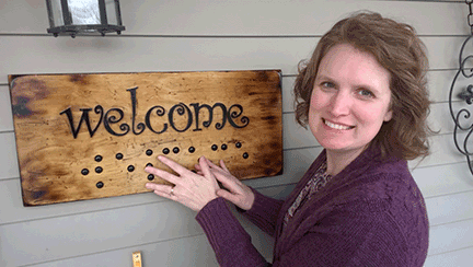 Haley Dare poses next to her print and Braille welcome sign.