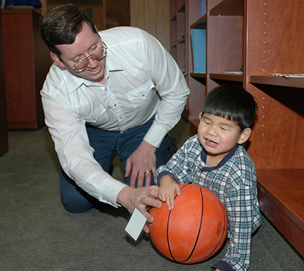 Bill Jacobs and his son, David, play on the floor with an audible ball.